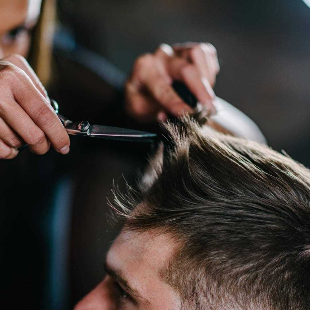 Person getting a haircut with scissors, focused on styling short hair.